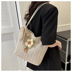 Detail of straw tote bag featuring floral accents and lace bow on a model shoulder