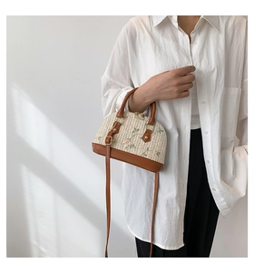 Detail of cream straw shell bag with floral embroidery and brown leather handle