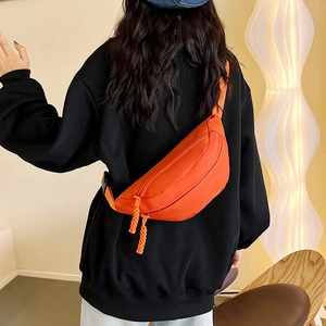 Orange solid color waist bag with zipper and woven rope detail shown on model