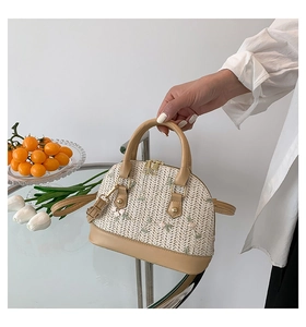 Detail of floral embroidery on a woven straw handbag with elegant leather trim finish