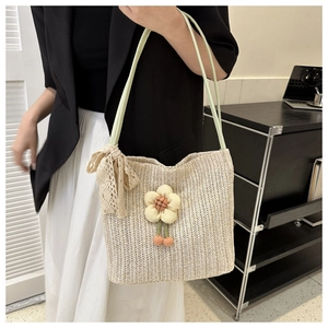 Detail of woven straw tote bag with fabric flower charm and lace bow on shoulder strap