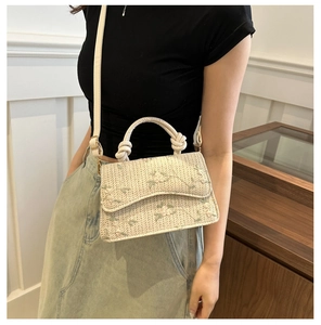 Detail of woven straw bag featuring delicate floral embroidery and knotted rope handle