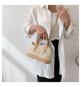 Detailed straw woven shell bag featuring delicate floral embroidery and leather trim handles