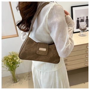 Brown vintage baguette bag with metal buckle shown on model in warm interior