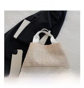 Détail de la texture tressée beige avec sangle contrastée en coton blanc sur le sac