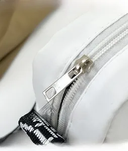 Detail of a white nylon shoulder bag featuring a silver metal zipper and geometric strap