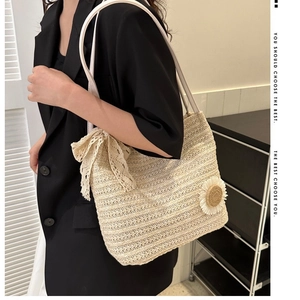 Beige straw woven tote bag with white lace bow and sunflower accent on model