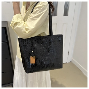 Detail of crocodile embossed black tote bag with elegant gold metal decorative tag