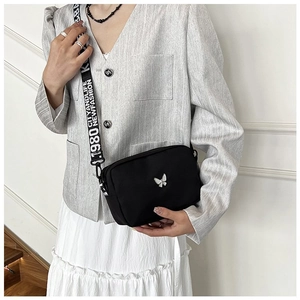 Detail of black nylon crossbody bag with silver butterfly charm and branded wide strap