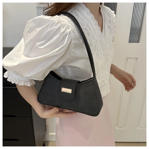Detail of minimalist black underarm bag with golden metallic buckle on matte leather