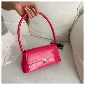 Dettaglio borsa in pelle verniciata rosa con fibbia dorata e manico cilindrico liscio