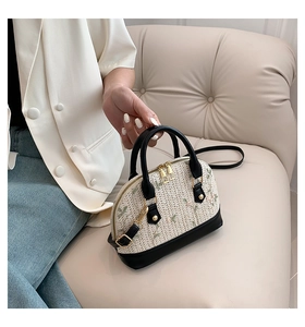 Detail of straw shell bag with floral embroidery and black leather handles