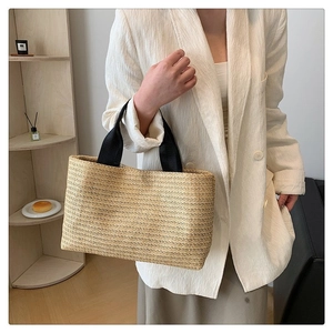 Détail du sac cabas en paille tissé main avec bandoulière noire dans un décor cosy