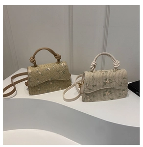 Detailed shot of woven straw crossbody bag with floral embroidery and knotted top handle