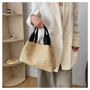 Gros plan d'un grand sac cabas en paille tressée avec des anses noires contrastantes