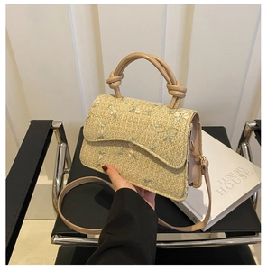 Detail of woven straw bag with floral embroidery and brown knotted leather handle
