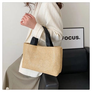 Gros plan d'un grand sac cabas en paille tressée avec des anses noires sur fond blanc