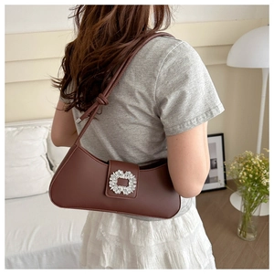 Detail of dark brown leather baguette bag with sparkling crystal buckle on shoulder strap