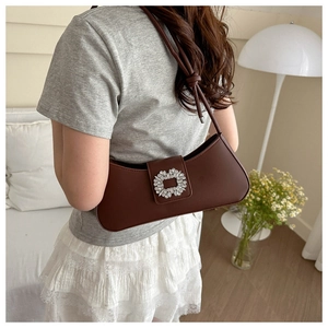 Close-up of a dark brown underarm bag featuring a sparkling square rhinestone buckle