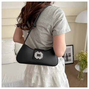 Detail of black crescent shoulder bag with crystal buckle shown on a model