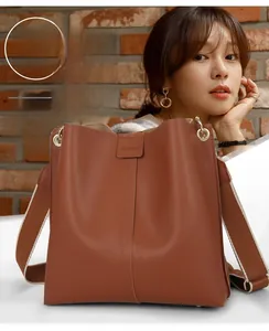 Detailaufnahme der karamellfarbenen Beuteltasche mit gewebtem Gurt und FASHION-Prägung
