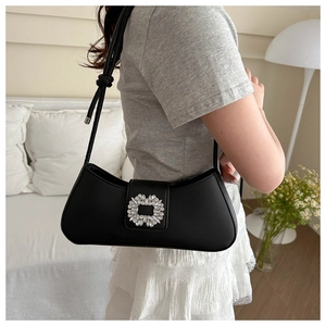 Detail of black baguette bag with rhinestone flower buckle worn on the shoulder