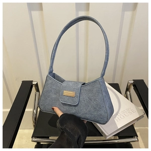 Detailed close-up of the textured denim blue baguette bag with gold metal hardware buckle