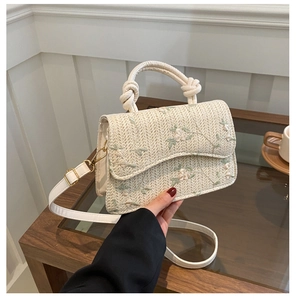 Detailed macro of handmade straw bag with floral embroidery and white leather strap