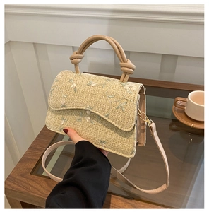 Detail of woven straw bag with delicate floral embroidery and elegant knotted handle