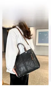 Détail du cabas en cuir noir à poches multiples avec patchwork vintage et anses brunes