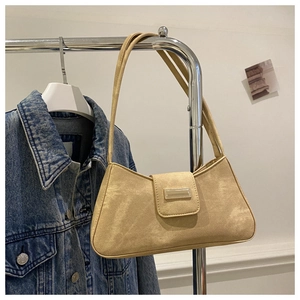 Detail of apricot baguette bag with matte texture and metallic bar on a metal hanger
