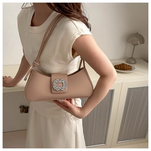 Detail of stylish beige baguette bag featuring a square rhinestone buckle on a matte leather