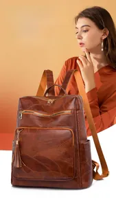 Detail of brown faux leather backpack with leaf embossing and metal tassel accents