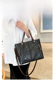 Détail du sac cabas en patchwork noir avec poignées marron et poches zippées