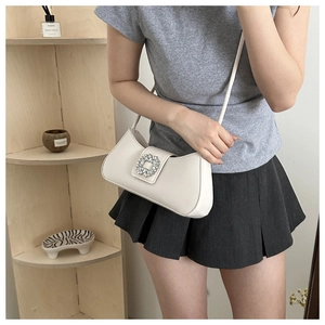 Detail of white leather crescent bag featuring a luxury square rhinestone buckle on flap