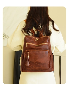 Detail view of a vintage dark brown leather backpack with multiple zippers and tassels