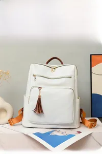 Close-up of white leather backpack with tassel detail and functional zipper pockets