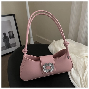 Detail of pink leather shoulder bag featuring a luxury rhinestone buckle and knot strap