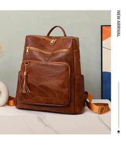 Detail of vintage brown textured leather backpack with gold zippers and tassel decor