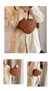 Close-up of heart-shaped rhinestone and metal rivet details on brown leather backpack