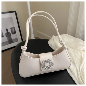 Macro detail of creamy leather underarm bag featuring a sparkling rhinestone square buckle