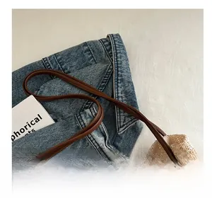 Detail of hand-woven straw tote with hollow crochet pattern and brown leather straps