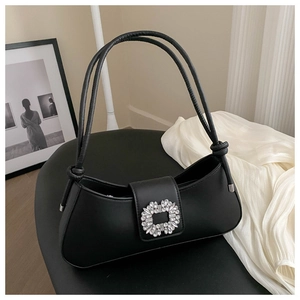 Close-up of black leather underarm bag with sparkling crystal buckle and rope knot strap