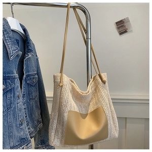 Detail of cream straw tote bag showing V-shaped woven texture and leather front pocket