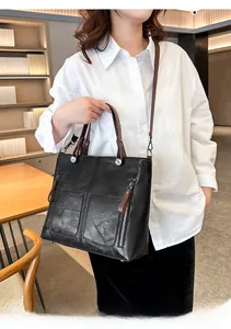 Détail du sac cabas en simili cuir noir avec zips argentés et anses marron en situation
