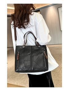Détail du sac cabas noir avec poignées marron et deux poches zippées sur le cuir