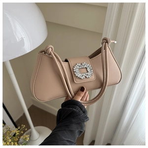 Detailed close-up of a khaki baguette bag with a sparkling crystal buckle and knotted strap