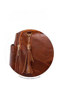 Detail showing the brown leather fringe tassel and golden metal chain on the backpack