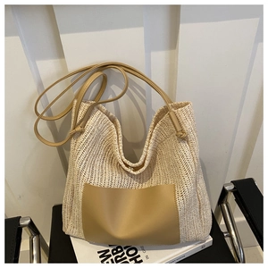 Close-up of woven straw tote bag featuring brown leather pocket and shoulder straps