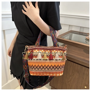 Close-up of bohemian straw bucket bag with vibrant tassels and wide geometric strap